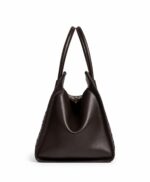 Side view of the York & Cali woven leather tote bag on its rolled top handles, showing the relaxed carry silhouette
